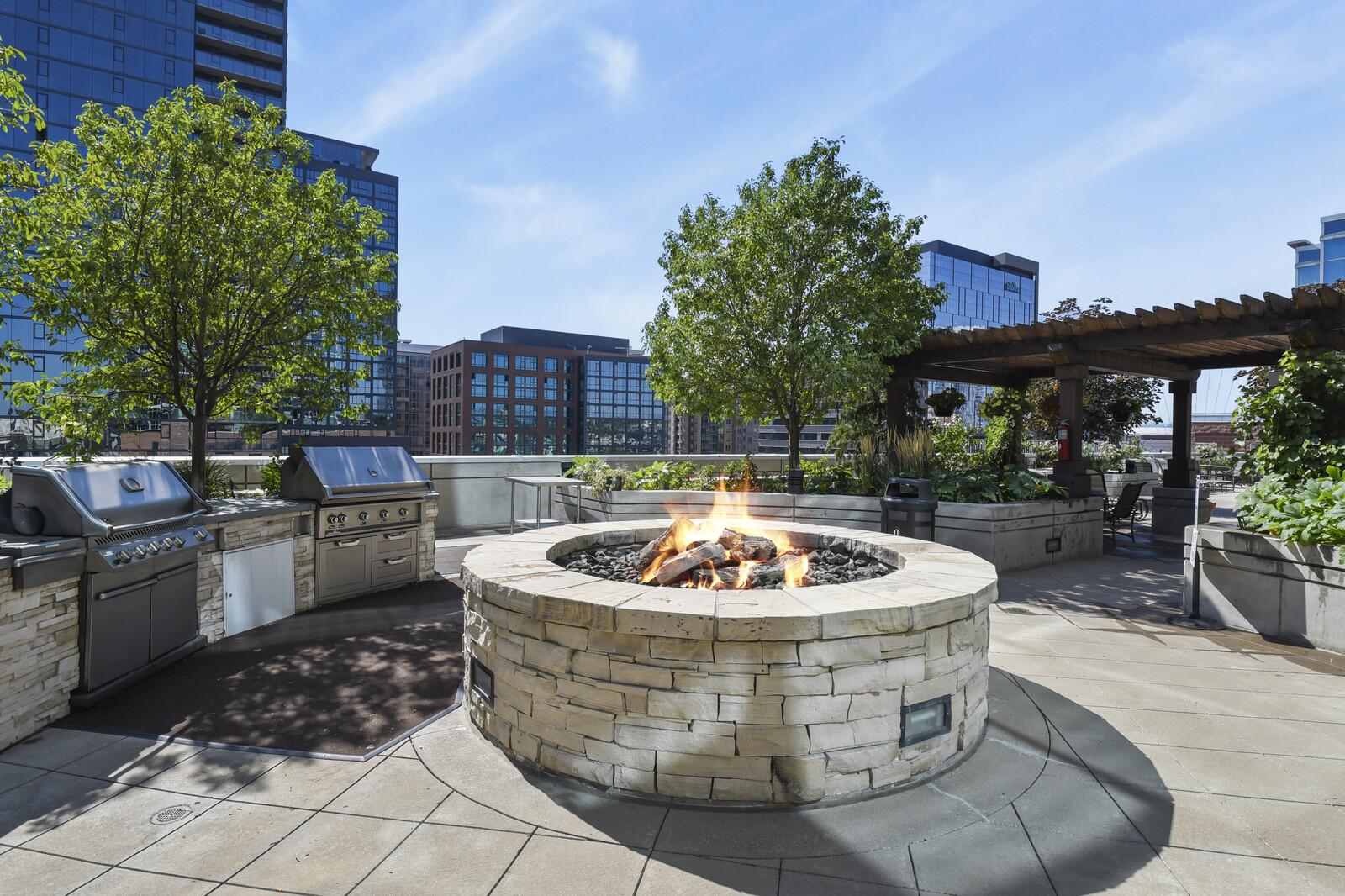 Outdoor terrace with a fire pit, trees and glass architecture at Dan’s past Denver listing